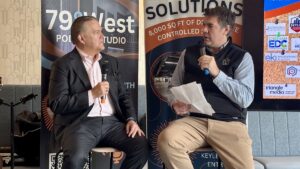 Two mean speaking with microphones at a business talk at 79 West in Pittsboro